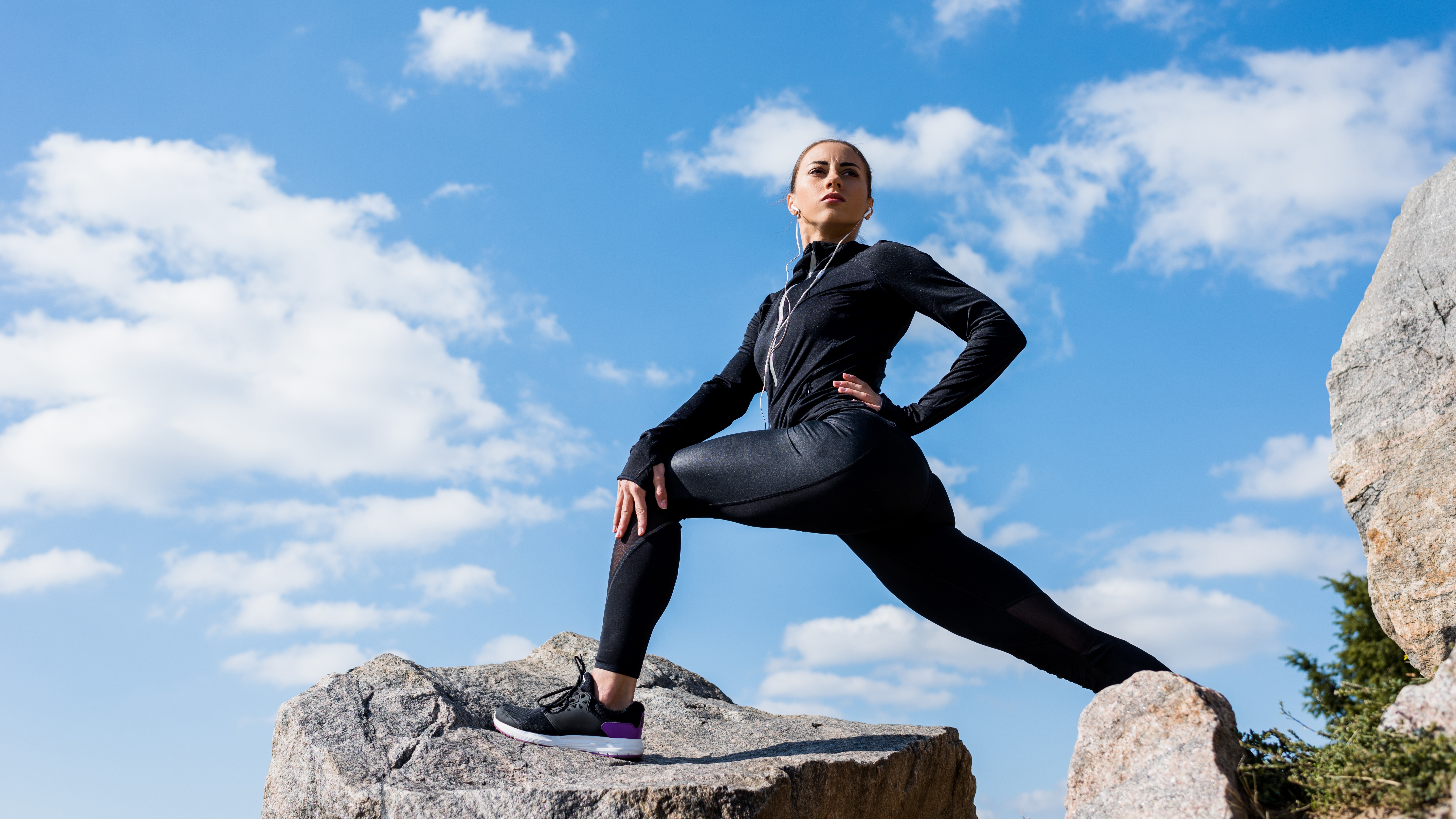 young fit woman stretching legs on rocks